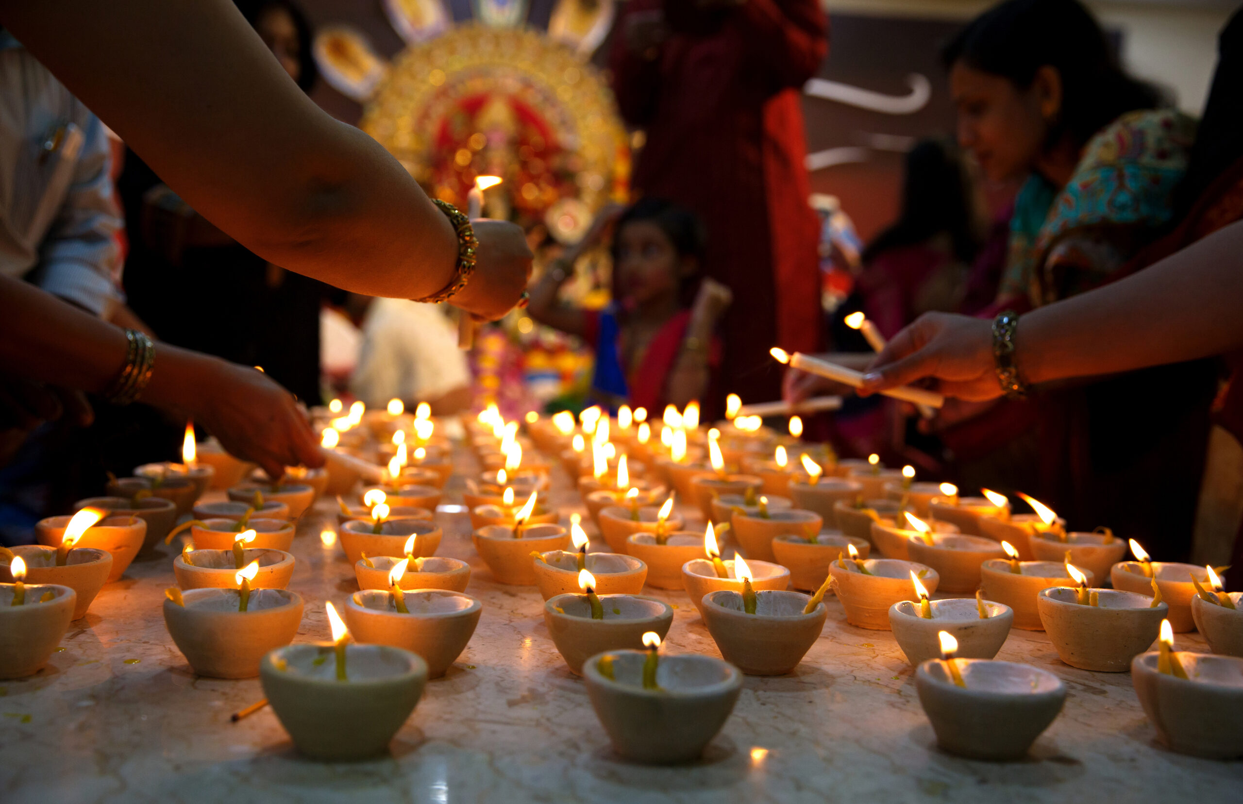 Oameni aprinzând lămpi cu ulei pentru Sandhi puja în timpul sărbătorii festivalului Durga Puja în Manama, Bahrain. Sursă foto: Dreamstime