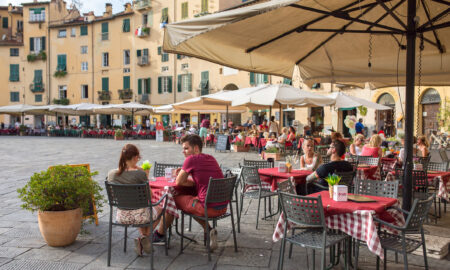 Persoane neidentificate care mănâncă preparate tradiționale italiene într-un restaurant în aer liber în centrul orașului Lucca, Italia. Sursă foto: Dreamstime