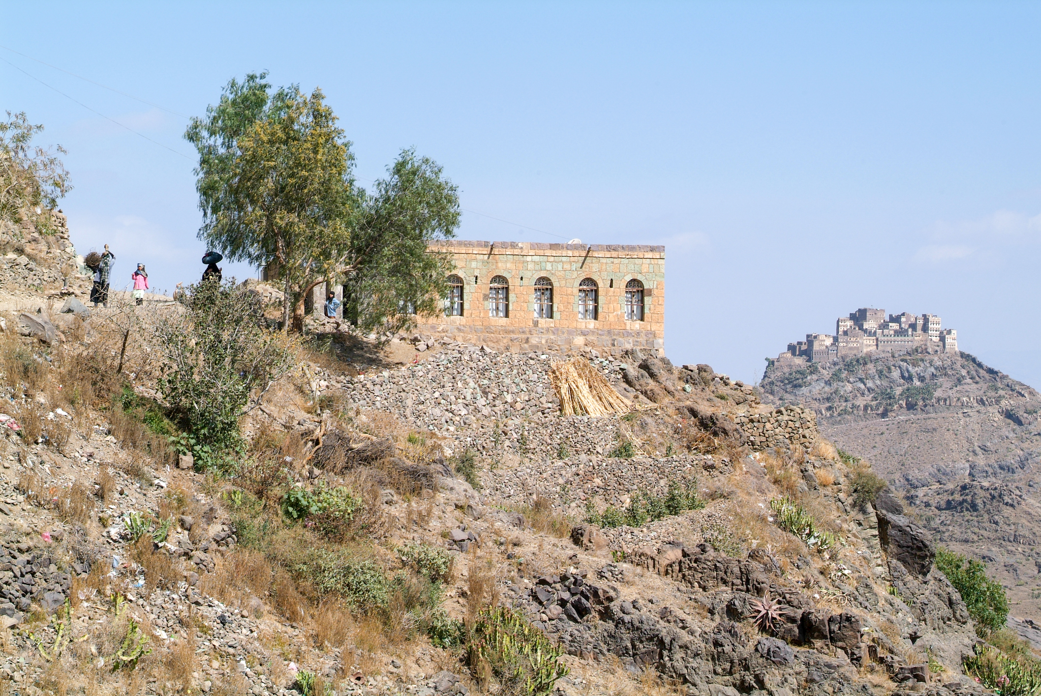 Priveliște către un munte format din pietre roșii, pe coasta căruia se află o casă veche decorată din orașul fortificat Kawkaban, Republica Yemen (sursă foto: dreamstime)