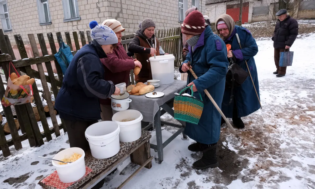 Iryna Viktorivna, în extrema stângă, distribuie mâncare caldă vecinilor săi din Kupiansk, regiunea Harkov. Sursă foto: The Guardian