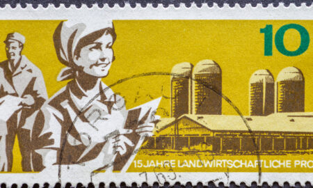 O ștampilă poștală din Germania, RDG, reprezentând un domeniu agricol cu silozuri și fermieri moderni, Sursa foto: dreamstime.com