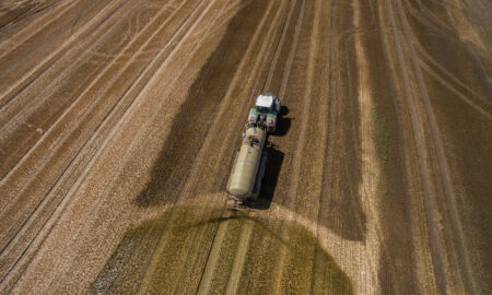 Vedere aeriană a unui tractor agricol cu o remorcă fertilizează un câmp agricol proaspăt arat cu gunoi de grajd, Sursa foto: dreamstime.com