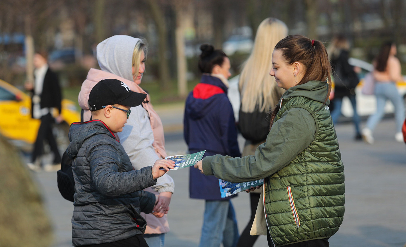 Un copil primește o broșură de la un voluntar de recrutare în armată.